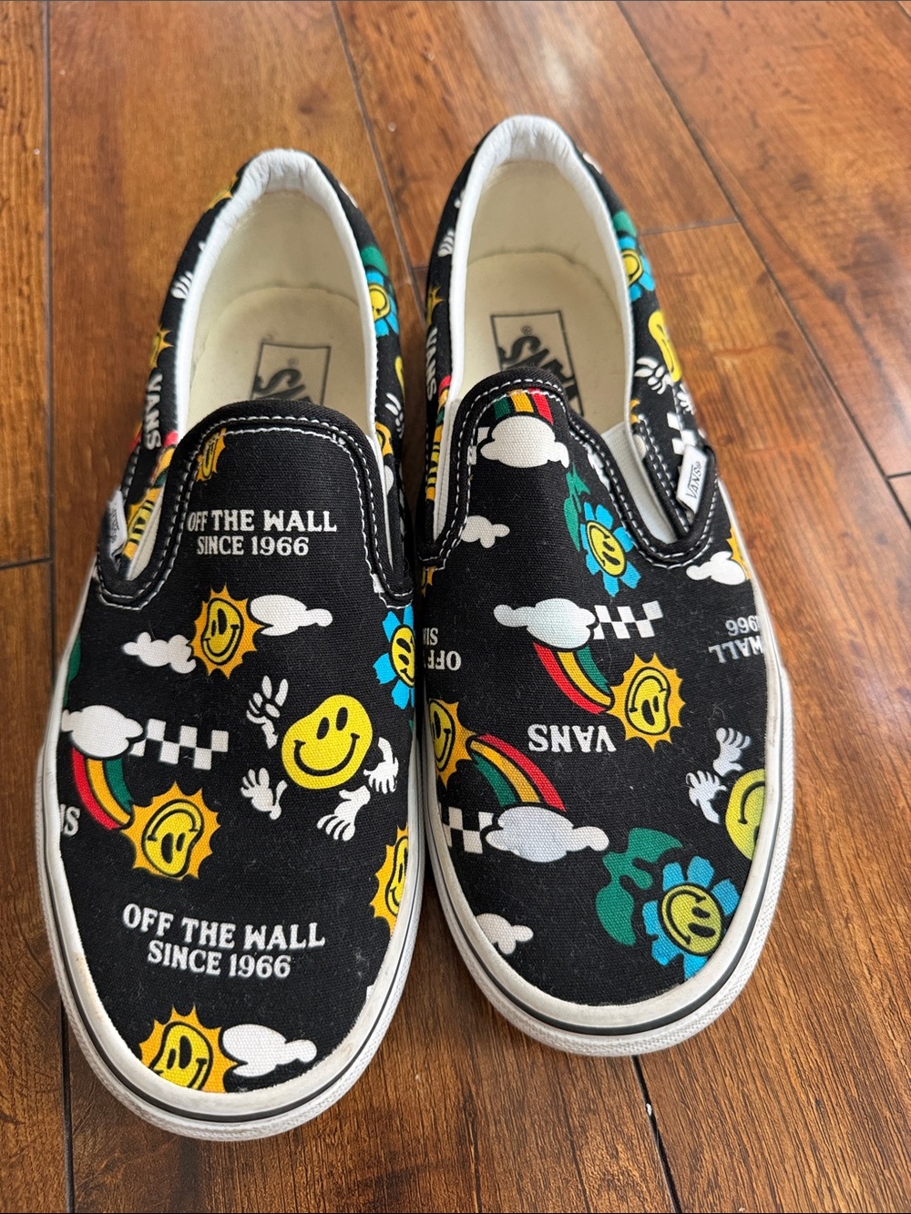 Vans Slip-On Sneakers in Black with Yellow Smiley & Rainbow Print